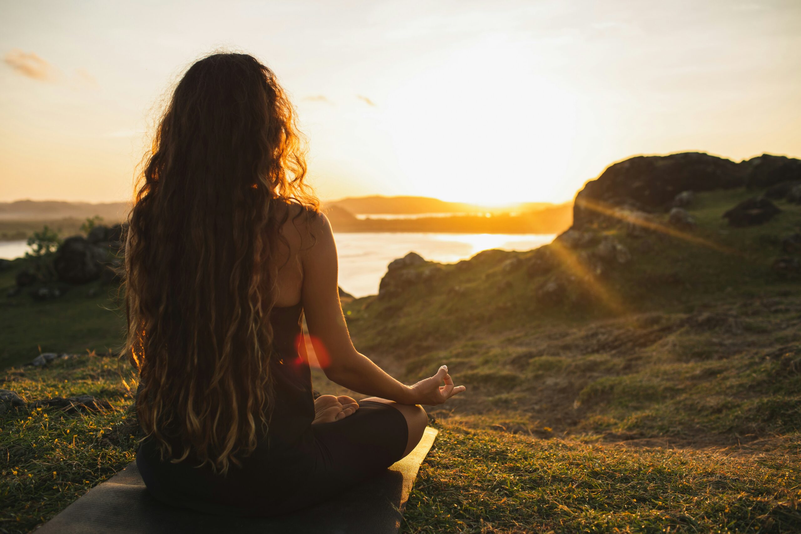 A woman meditating on the beach at sunrise