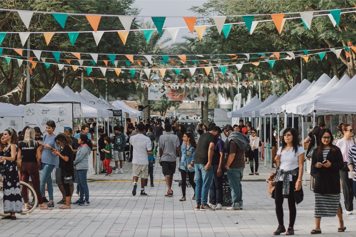 people walk around an outdoor food and craft festival